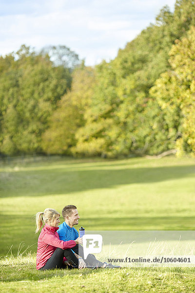 Junges Paar in Sportkleidung entspannt sich im Park
