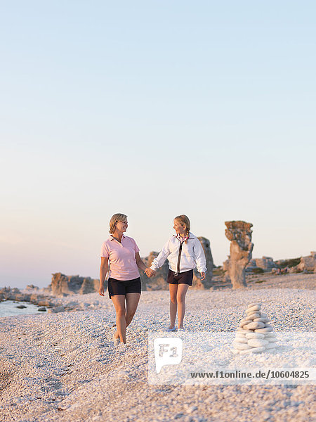 Mother with daughter walking on beach