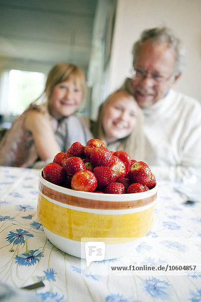 Erdbeeren in Schale  Großvater mit Enkelinnen im Hintergrund