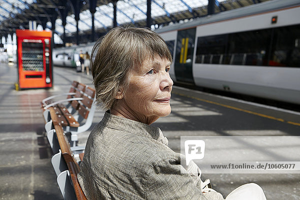 Ältere Frau auf dem Bahnhof sitzend