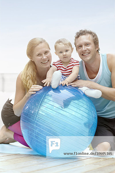 Smiling couple and baby boy with fitness ball