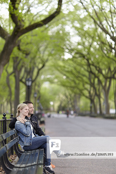 Smiling couple sitting on bench in park
