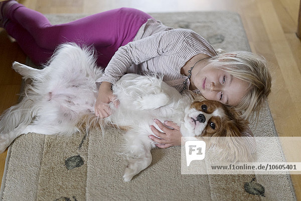 Mädchen liegend mit Hund auf Teppich