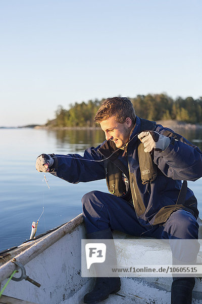 Junger Mann beim Fischen auf einem Boot