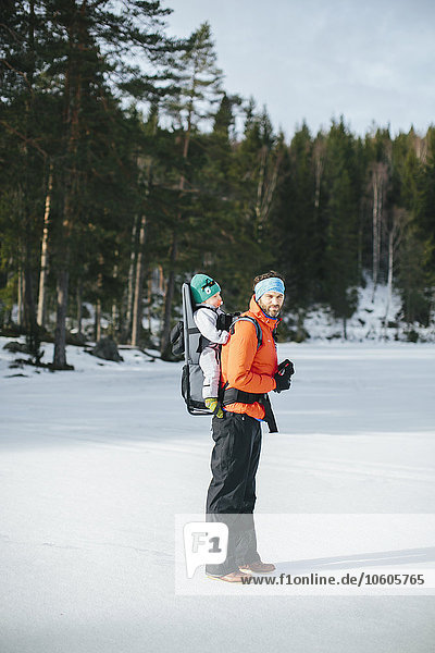 Mann beim Winterspaziergang mit Baby in Babytrage
