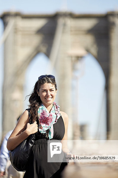 Frau in schwarzem Kleid mit Brooklyn Bridge im Hintergrund