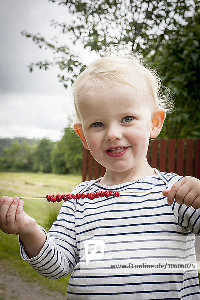 Small boy holding berries on thread