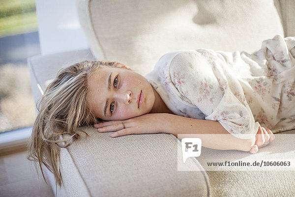 Porträt eines blonden Mädchens auf dem Sofa liegend