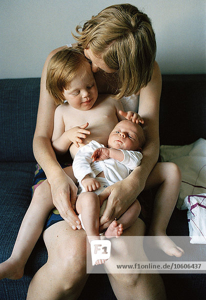 Eine Mutter mit zwei Kindern auf dem Schoß  Schweden.