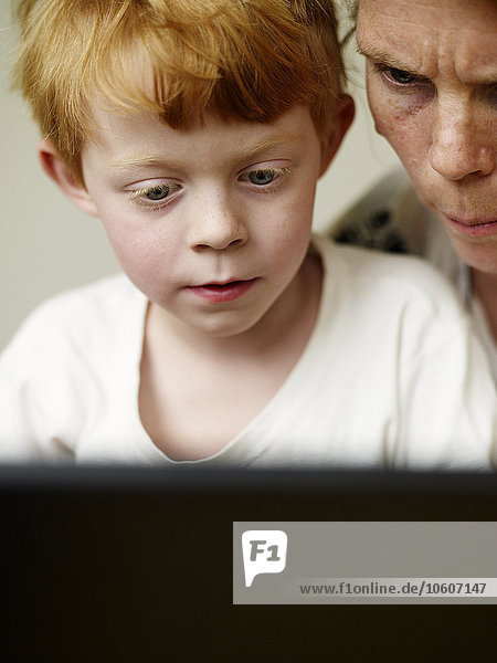Ein Junge und seine Mutter schauen auf einen Computer  Schweden.
