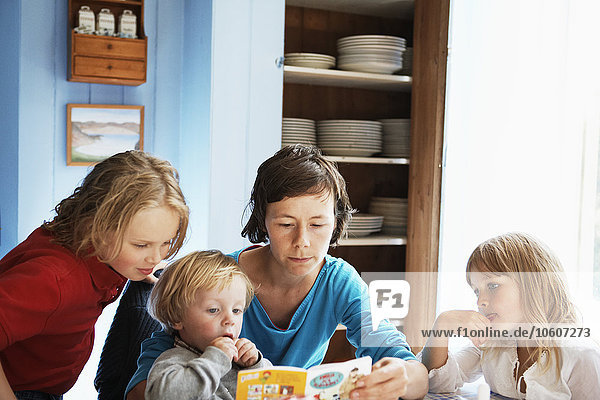 Mother with three children sitting in a kitchen.