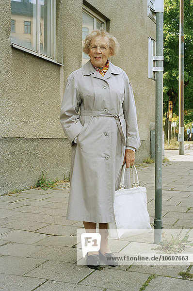 Ältere Frau an der Bushaltestelle