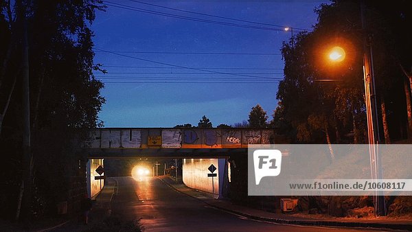 Krankenwagen mit Blinklichtern fährt nachts über die Brücke