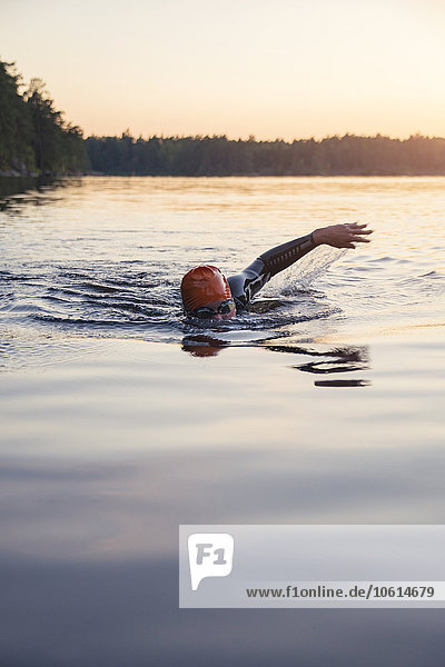 Person swimming at sunset