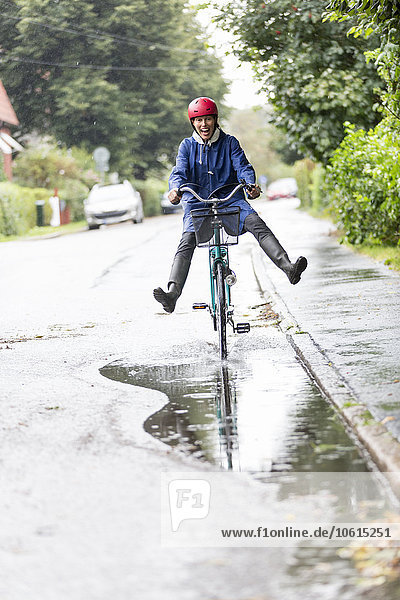 Woman riding bicycle through puddle