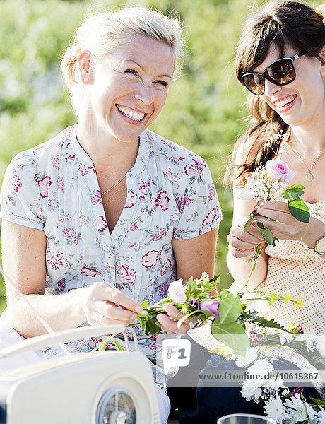 Lächelnde Frauen machen Blumenkränze