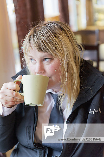 Frau trinkt aus einer Tasse in einem Cafe