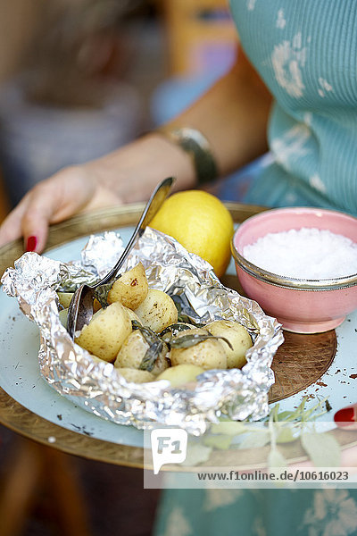 Woman carrying tray with baked potatoes