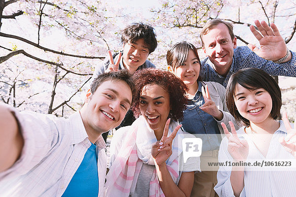Multi-ethnic group of friends enjoying cherry blossoms blooming in Tokyo