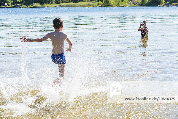 Junge läuft im Wasser  Mutter fotografiert