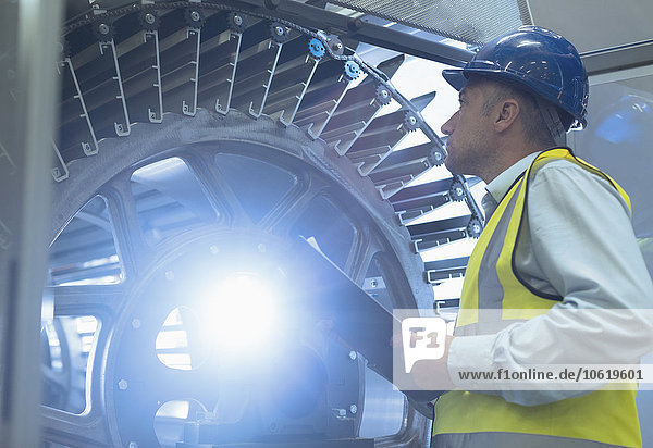 Supervisor with clipboard examining machinery in printing plant