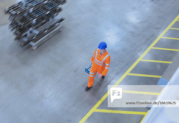 Worker in reflective clothing walking with toolbox in factory