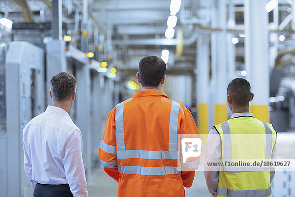 Workers and supervisor standing in factory corridor