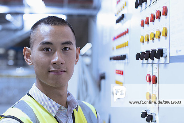 Portrait confident worker at control panel in factory