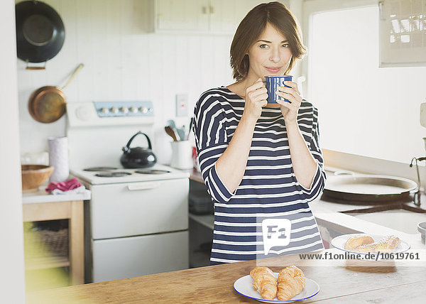 Brunette woman drinking coffee in kitchen