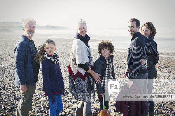 Portrait lächelnde Mehrgenerationen-Familie am sonnigen Strand