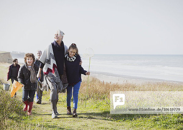 Mehrgenerationen-Familienwanderung auf einem grasbewachsenen Strandweg