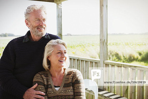 Lächelndes Seniorenpaar mit Blick auf die sonnige Veranda