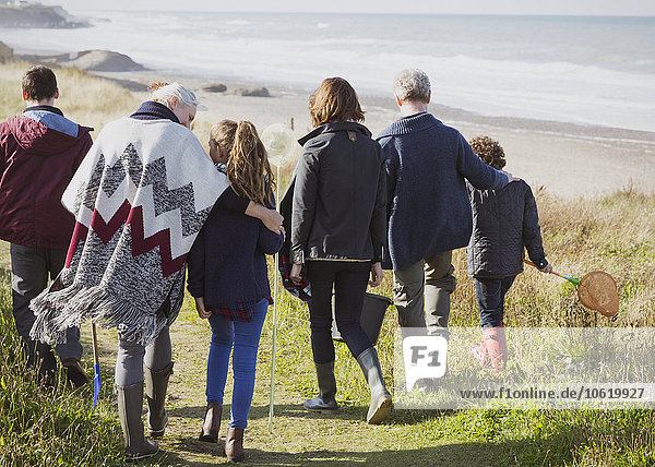 Multi-generation family walking on sunny grass beach path