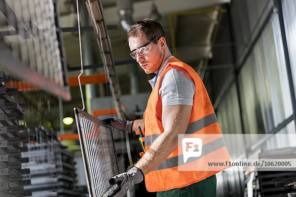 Fokussierter Arbeiter hält Stahlteil in der Fabrik
