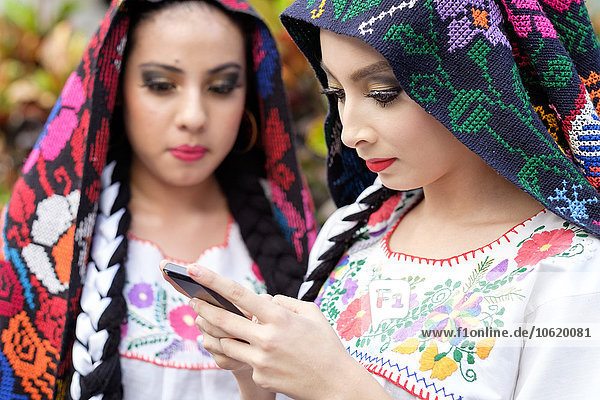 Mexiko  Jalisco  Xiutla-Tänzerin  folkloristische mexikanische Tänzerin mit Smartphone
