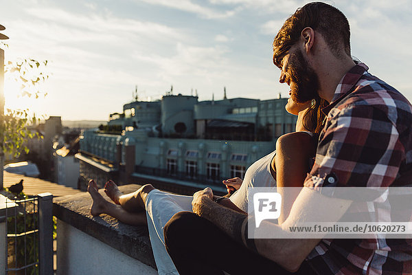 Österreich  Wien  Junges Paar genießt romantischen Sonnenuntergang auf der Dachterrasse