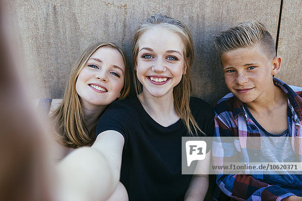 Three teenagers outdoors posing for a selfie