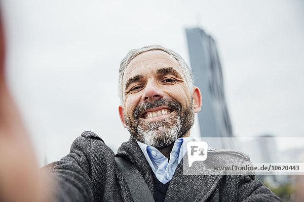 Österreich  Wien  Porträt eines Geschäftsmannes  der einen Selfie mit seinem Smartphone nimmt.