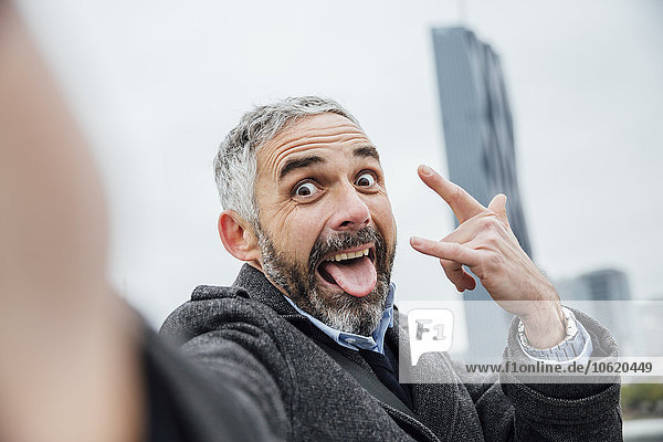 Austria  Vienna  portrait of businessman pouting mouth while taking a selfie with his smartphone