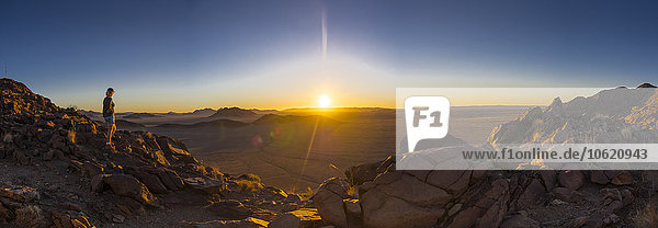 Afrika  Namibia  Hardap  Hammerstein  Kulala Wilderness Reserve  Tsaris-Gebirge  Frau steht bei Sonnenuntergang in der Namib-Wüste