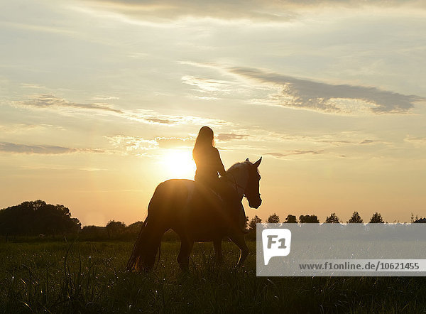 Junge Frau reitet in den Sonnenuntergang