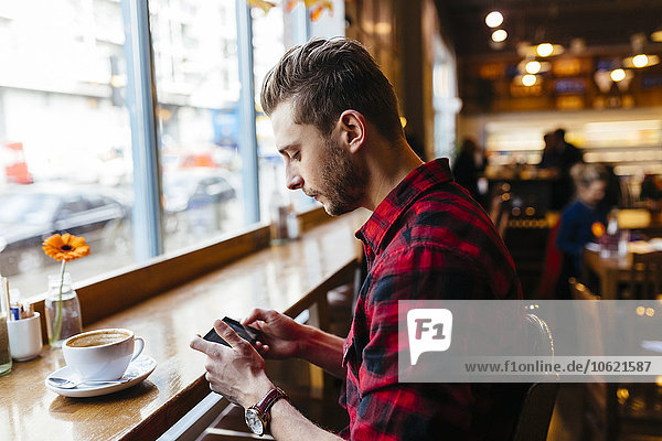 Man in a coffee shop looking at cell phone