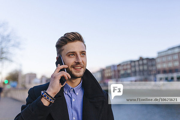 Ireland  Dublin  portrait of young businessman telephoning with smartphone