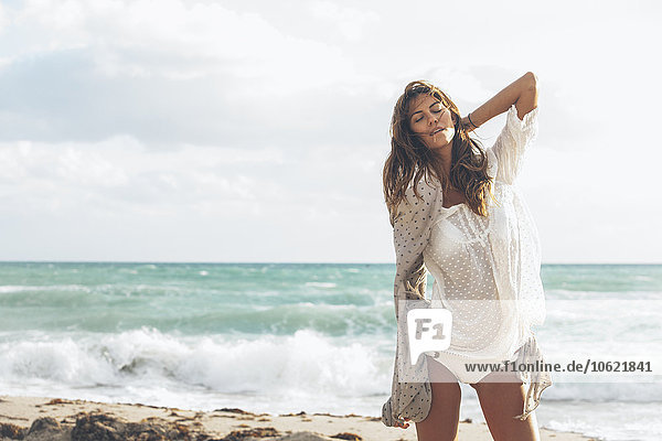 Hübsche junge Frau in Strandkleidung am Strand