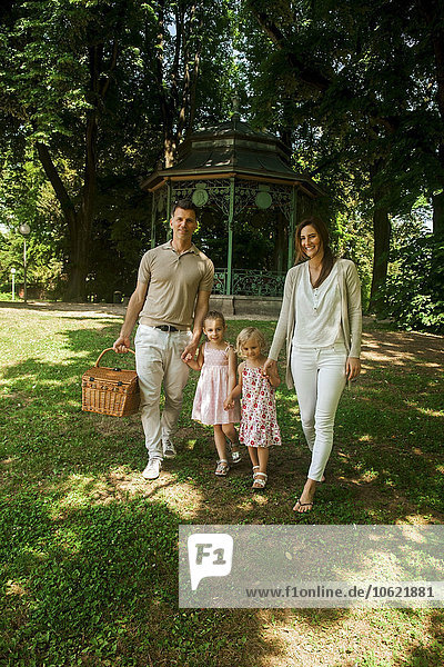 Happy family in park  parents carrying picnic basket