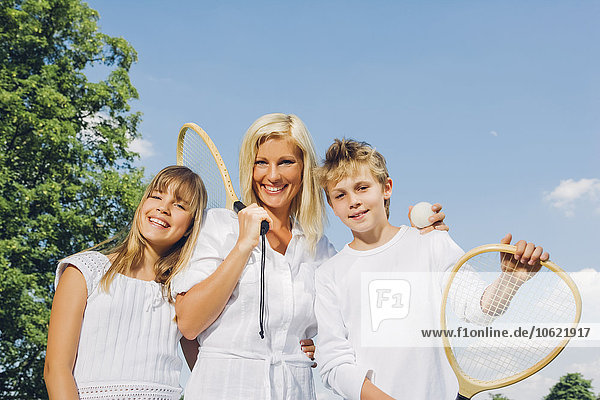 Porträt der glücklichen Frau und ihrer Kinder mit Tennisschlägern