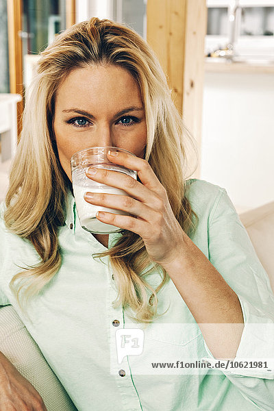 Blonde Frau trinkt ein Glas Milch.