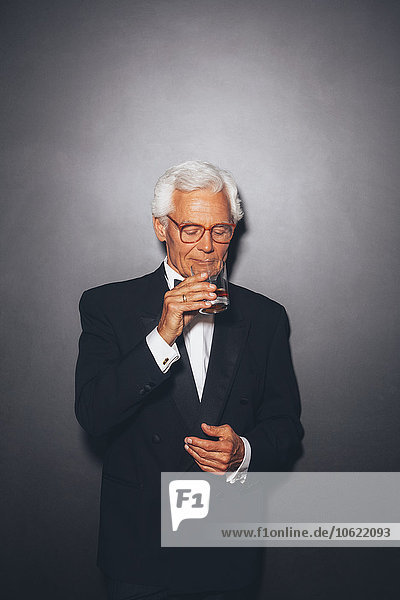 Confident elegant senior man drinking from tumbler
