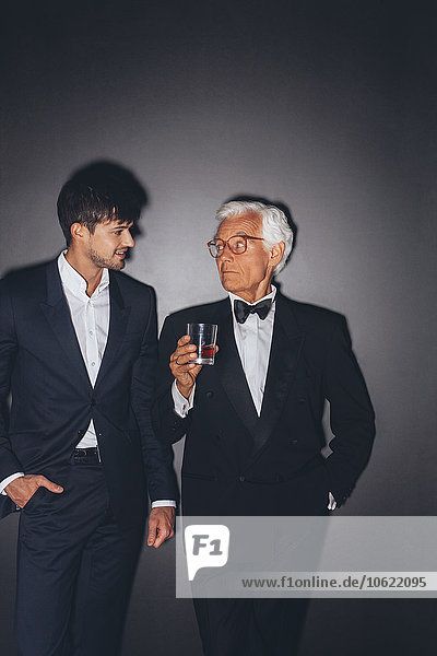 Young man and elegant senior man holding drink