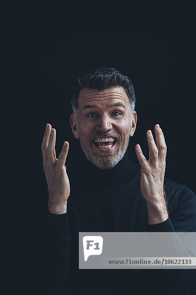 Portrait of excited man wearing black turtleneck in front of black background